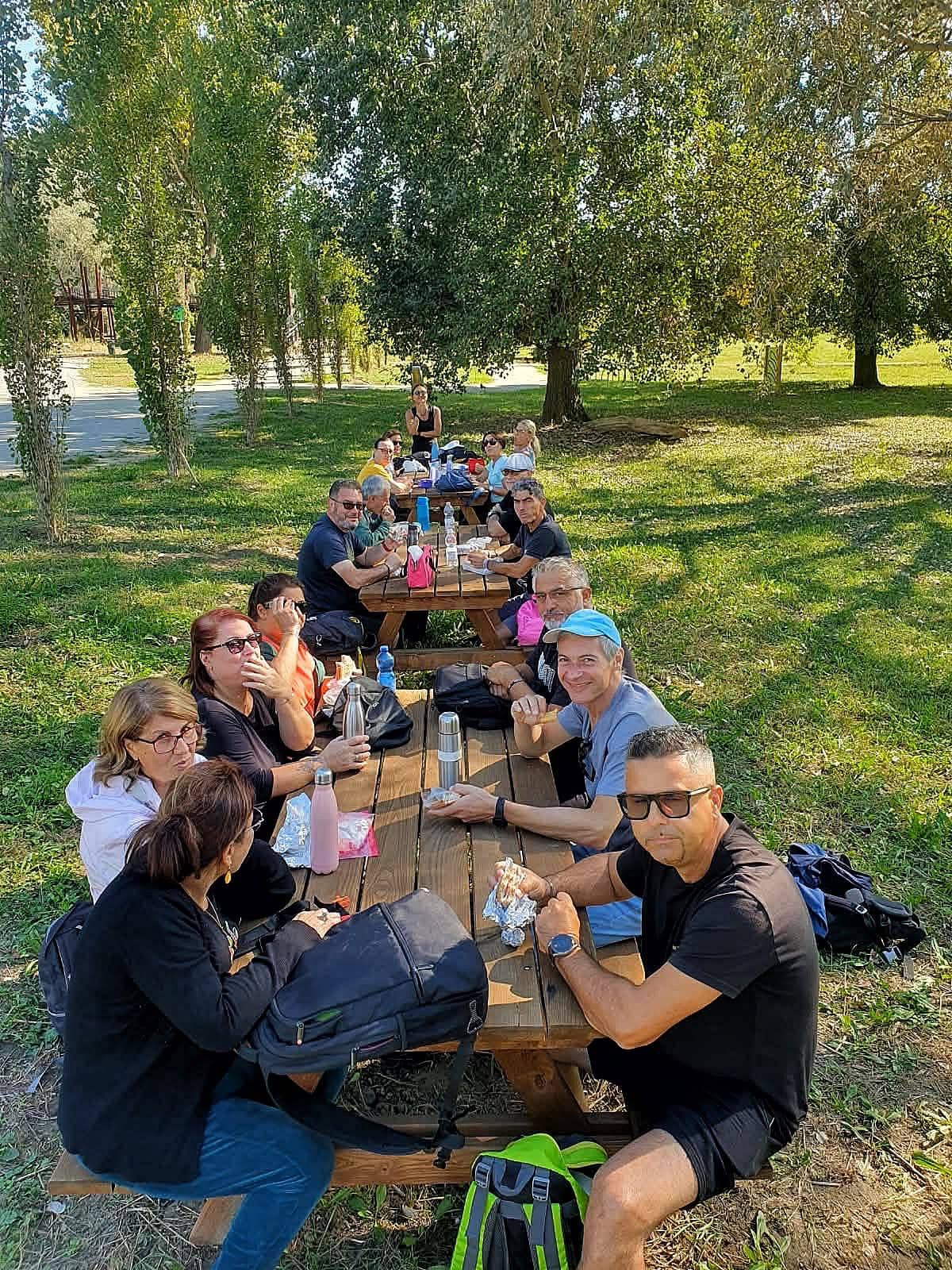 Pranzo al sacco del gruppo su lunghi tavoli di legno in un parco
